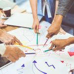 Creative idea teamwork concept. Group of multiethnic diverse team, business partner, or college students in project meeting at modern office. Five people pointing at lightbulb drawings.