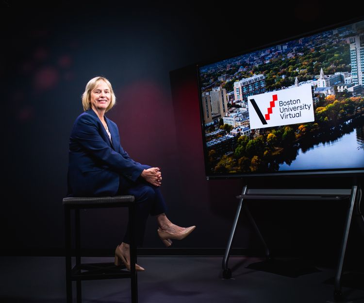 Wendy Colby sits on a stool in a studio, smiling. A screen displays "Boston University Virtual" with a cityscape background. The mood is professional and inviting.