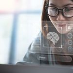A woman with glasses focuses intently on a laptop, surrounded by virtual screens displaying AI and neural network graphics, conveying a futuristic tech vibe.