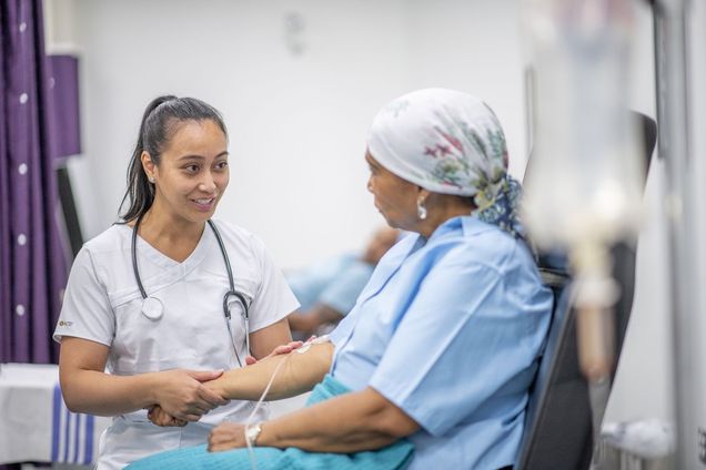 Young nurse with woman cancer patient in oncology unit.