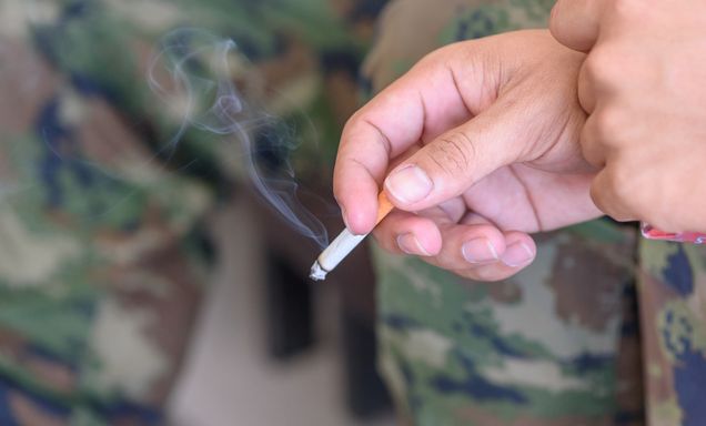 Hand of a veteran or soldier with a lit cigarette