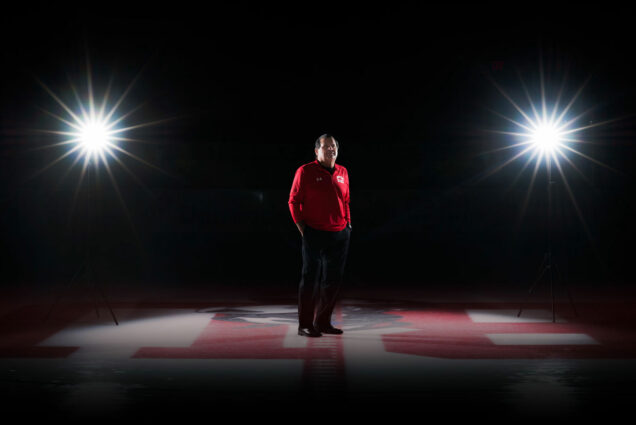 Portrait of Mike Eruzione standing at center ice in a hockey rink.