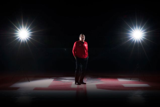 Portrait of Mike Eruzione standing at center ice in a hockey rink.