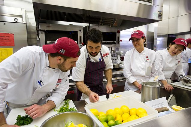 Culinary Arts student Sam Kauff, left, Kyoungah Kim (GRS'16), from right, and  Claudia Catalano (MET'16) watch chef Barry Maiden demonstrate his knife skills March 19, 2015. The class was prepping a meal for that evening's Flavors of the South, with Barry Maiden event at 808. Photo by Cydney Scott 