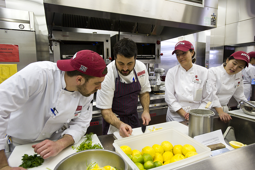 Culinary Arts student Sam Kauff, left, Kyoungah Kim (GRS'16), from right, and  Claudia Catalano (MET'16) watch chef Barry Maiden demonstrate his knife skills March 19, 2015. The class was prepping a meal for that evening's Flavors of the South, with Barry Maiden event at 808. Photo by Cydney Scott 
