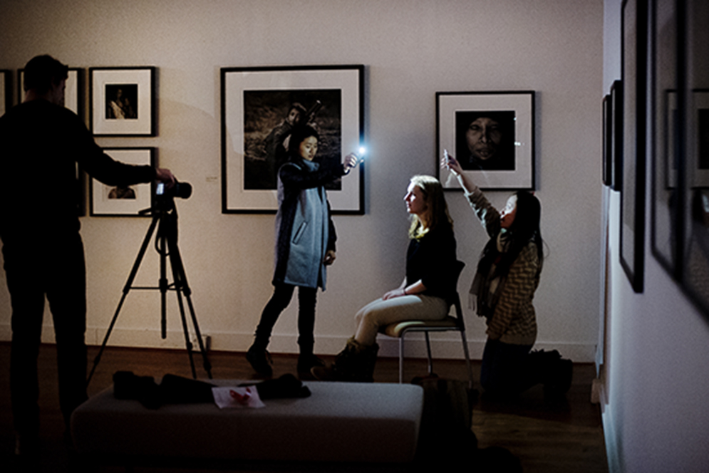 Caitlin Shawaker (CFA 15) poses while Joyee Zhou  (left) (CFA 18) and Yanyan Zhou use lights during an interactive  photography portrait project on Monday, March 2, 2015. Digital Photography students invited the BU community to an interactive  exploration of photography and identity.They had the opportunity to collaborate with the students to choose and create the different elements of their portrait including, backdrop, props, and pose. Photo By Jackie Ricciardi 