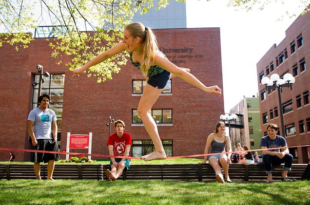 Isabell Whiteley (CAS'15) takes on slacklining in front of the Metcalf Science Center May 6, 2015 while her friends Anthony Aguayza (CAS'15) from left, Jared Brill (COM'18) Katie Lefton (CAS'16) and Kota Weaver who works at Photonics look on. The group met while rock wall climbing. Photo by Cydney Scott