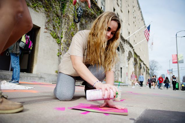 student stencils with chalk paint on Commonwealth Avenue during a Boston University College of Fine Arts event 