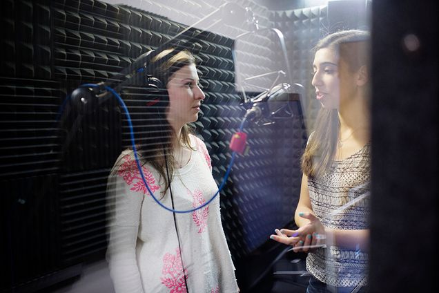 COM students Golda Fogel (COM 17) and Jordyn Danielson (COM 17) record in a sound booth during a COM 201 course. 