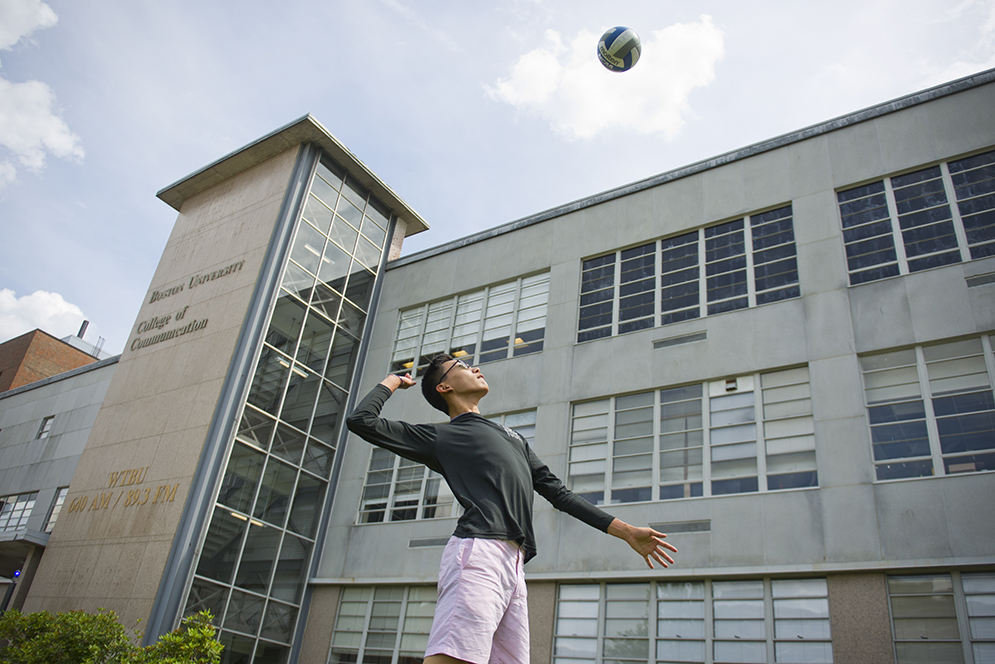 Steven Xie (CAS'17) playing volleyball on the COM lawn