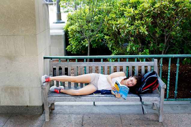 Sarah Saccoach (SAR'17) reads a book, <i>Born to Run</i>, on a bench