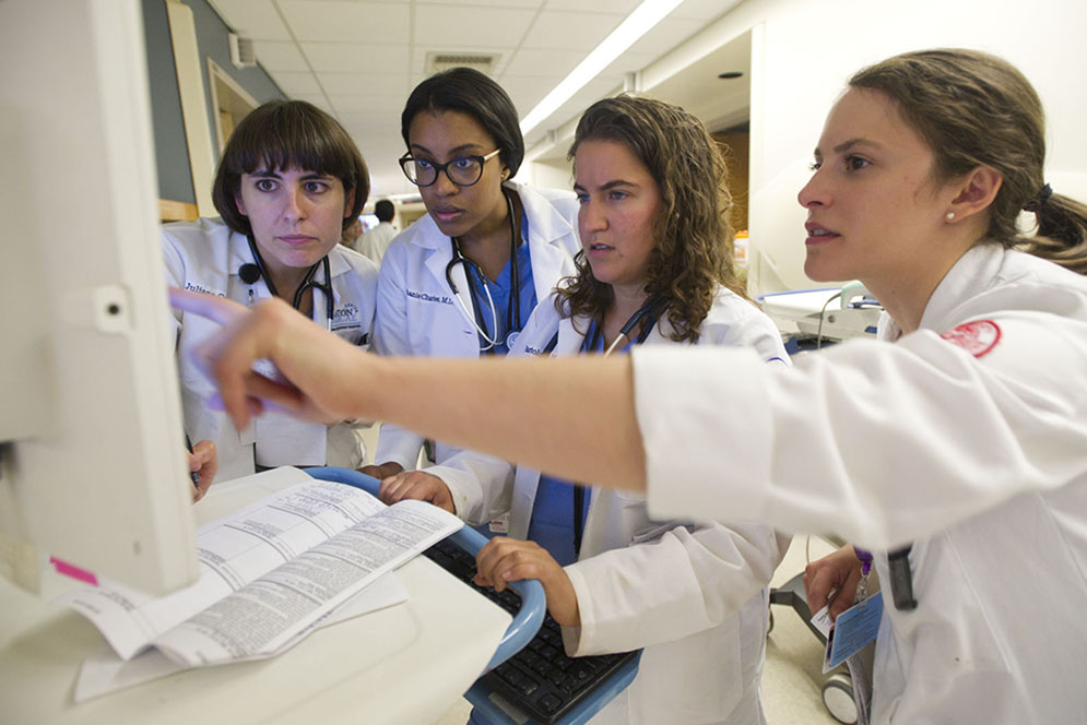 Juliana Castedo, intern, from left, Stephanie Charles, PGY-3, Julie Bartolomeo, intern (BUSM'15), and Veronica Torres, MS4, (BUSM'16) review plans for patients and place orders for patients at BMC July 17, 2015. Photo by Cydney Scott