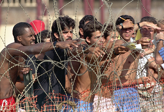 Cuban refugees detained during the 1994 Cuban Rafter Crisis hand notes with their names to Navy personnel so that they can get on the list of detainees at the Guantanamo Bay Naval Base in Cuba.