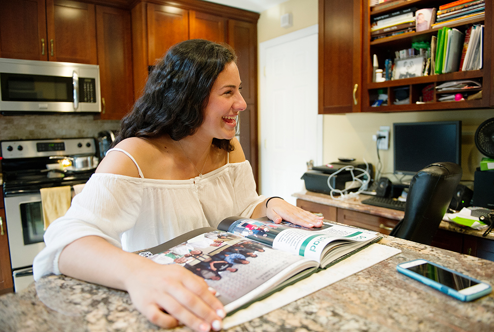 Jessica Silva sits in her kitchen looking through her high school yearbook