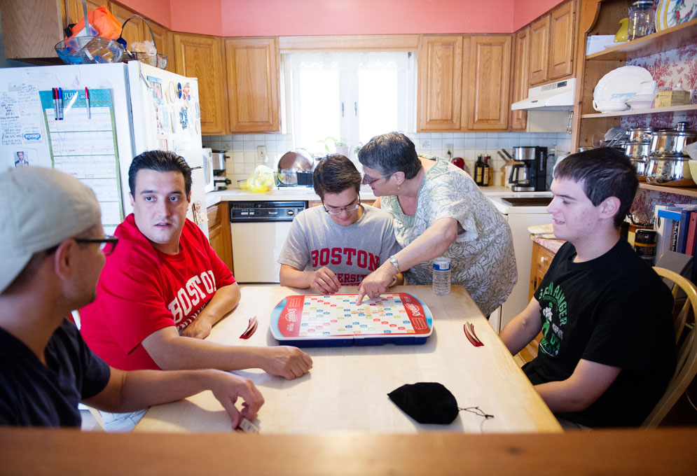 Sam's mother helps him during a family game of scrabble with his three older brothers.