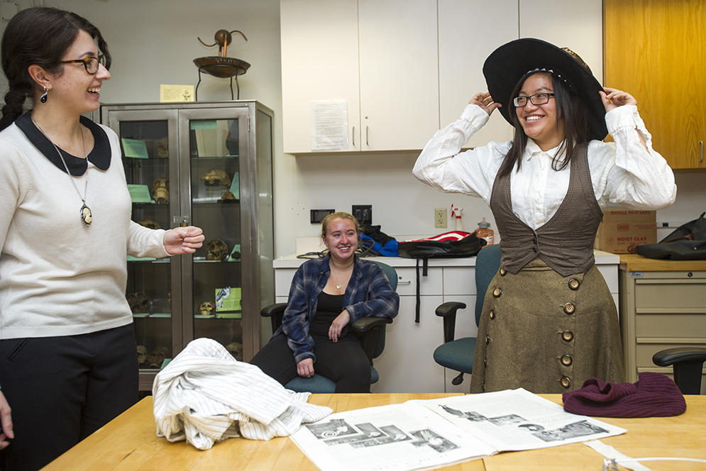  At an Archaeology Society meeting, Audrey Tjahjadi (CAS'17), at right, tries on some period clothes during a presentation being made by Jade Luiz (GRS'17), left, and Ilaria Patania (GRS'16), not pictured, about Victorian-era clothing October 28, 2015. At center is Samantha Kelley (CAS'19). Photo by Cydney Scott