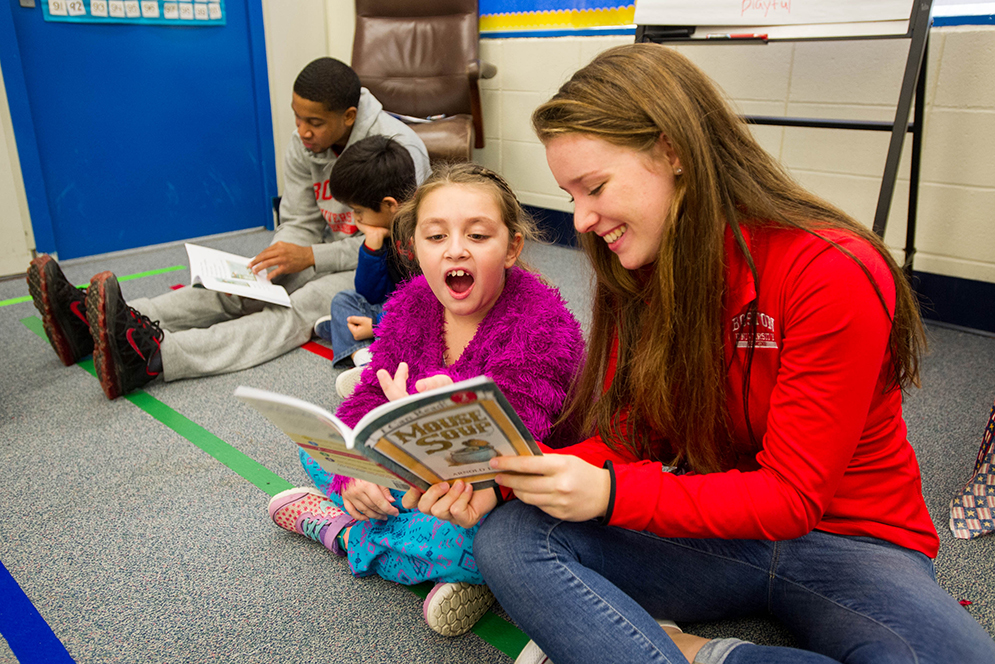 Ariales Ortiz, center, and Emma Lauder (CAS'18) at right, of the women's lightweight rowing team, read Mouse Soup together in Kathleen Chiong's second grade class at Jackson Mann Elementary in Allston December 11, 2015. At left Kamali Chambers (CGS'18), who plays for BU men's basketball, reads to Randy Guzman. Photo by Cydney Scott