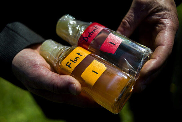 Virginia Tech professor Marc Edwards shows the difference in water quality between Detroit and Flint after testing, giving evidence after more than 270 samples were sent in from Flint that show high levels of lead during a news conference on Tuesday, Sept. 15, 2015 outside of City Hall in downtown Flint, Mich. (Jake May/The Flint Journal via AP) MANDATORY CREDIT LOCAL TV OUT; LOCAL INTERNET OUT