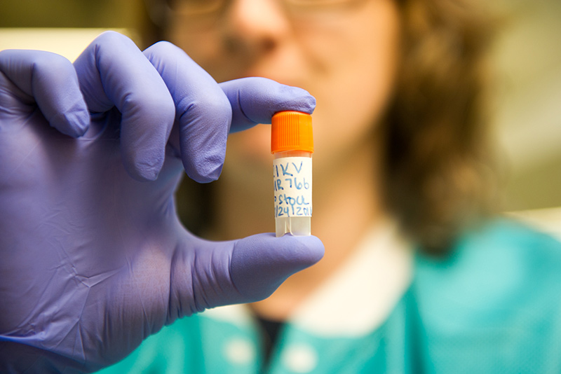 Researcher at Boston University NEIDL facility holds a vial containing a sample of the Zika virus