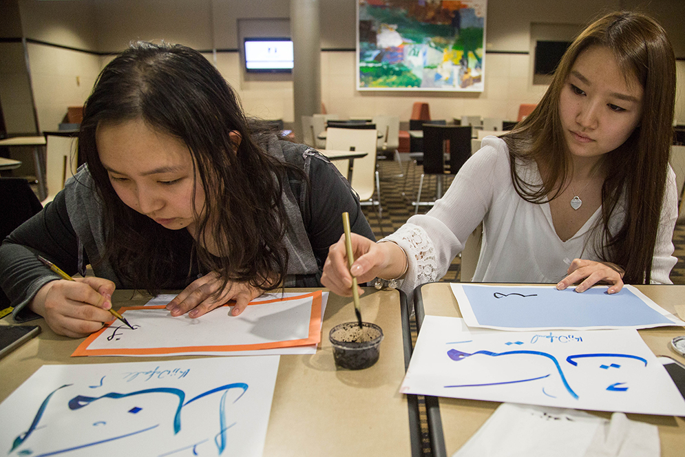 Judy Phyu (Questrom '17), right, and Amanda Valentina (Questrom '16) practice writing their names in Arabic at CalligraTea, an event where participants learned to write their names in Arabic. The event was jointly hosted by BU International Society and BU Arabic Society at the GSU backcourt in an effort to encourage international arts among the student body. Photo by Pankaj Khadka (COM'16)