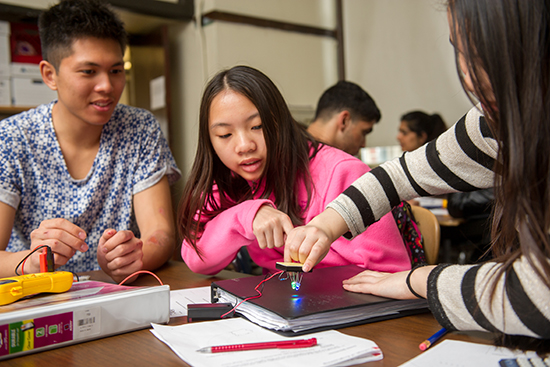 Helped by Carlo Quicho (ENG’18) (left) Ada Tsang, 14, and Li Yu, 14, work on an experiment using voltmeters and LEDs at the Josiah Quincy