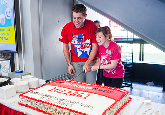 Martine Subey and Kyle Ortman cut cake celebrating The Million Hours Project 