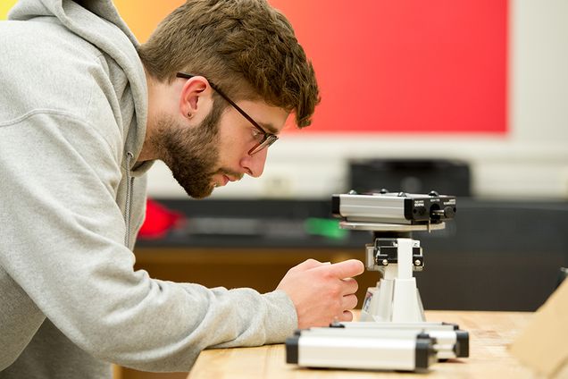 Zach Linck (CAS'17) weighs a cart to be used in a lab on gravity during CAS AS 101 The Solar System in CAS