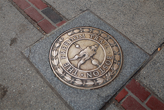 A sidewalk marker denoting the direction of the Boston Freedom Trail