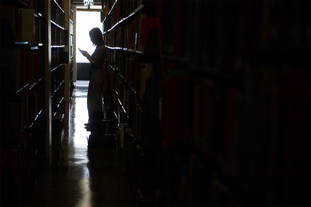 Silhouette of a person browsing the stacks at Mugar Memorial Library at Boston University