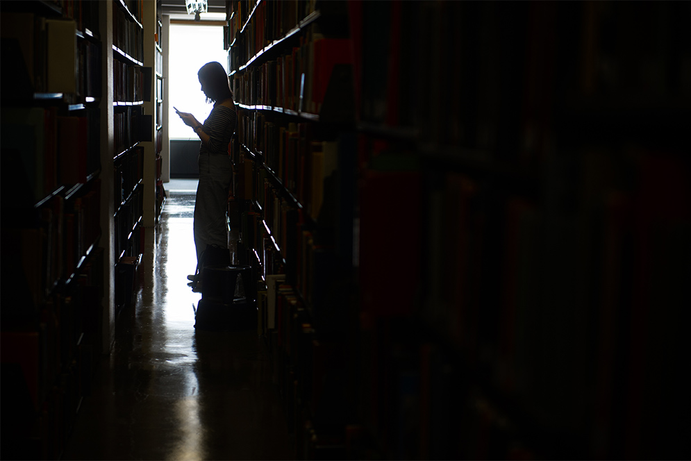 Silhouette of a person browsing the stacks at Mugar Memorial Library at Boston University
