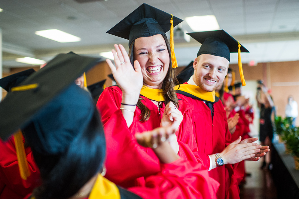 Jackie Price gives a high five to fellow graduate Sejal Thaker as Cole Turno looks on during the Physician Assistants Commencement ceremony.