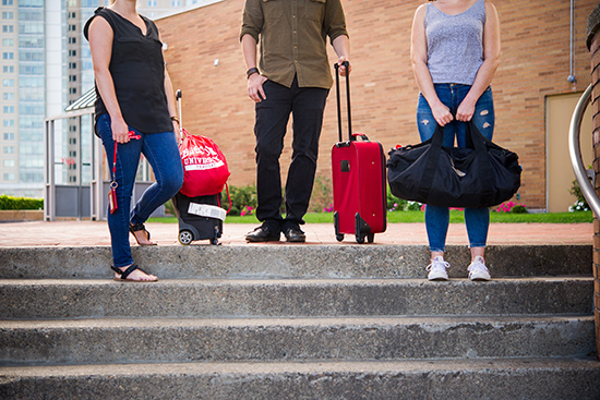 students holding suitcases and duffle bags