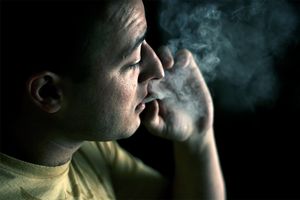 young man smoking weed in a dark room