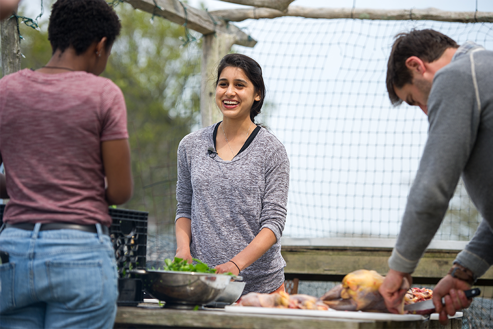 Boston University Gastronomy students Valencia Baker and Sonia Dovedy help Chef Chris Fischer prepare dinner at Beetlebung Farm in Chilmark, Massachusetts