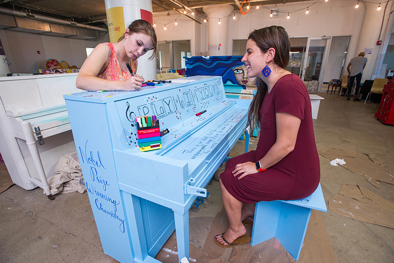 Alexis Courtney-Young (GRS’18), left, and Gabrielle Fleming (GRS’19) paint a piano for the Street Pianos Boston 2016