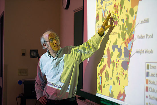 Richard Primack in a classroom giving a lecture in front of a projector screen