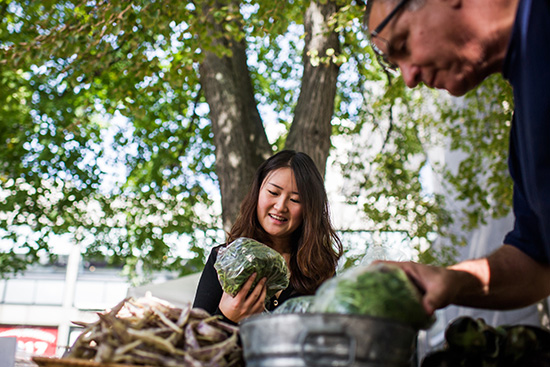 Angela Yuan (CAS’18) looks at a bag of vegetables at BU Farmers Market