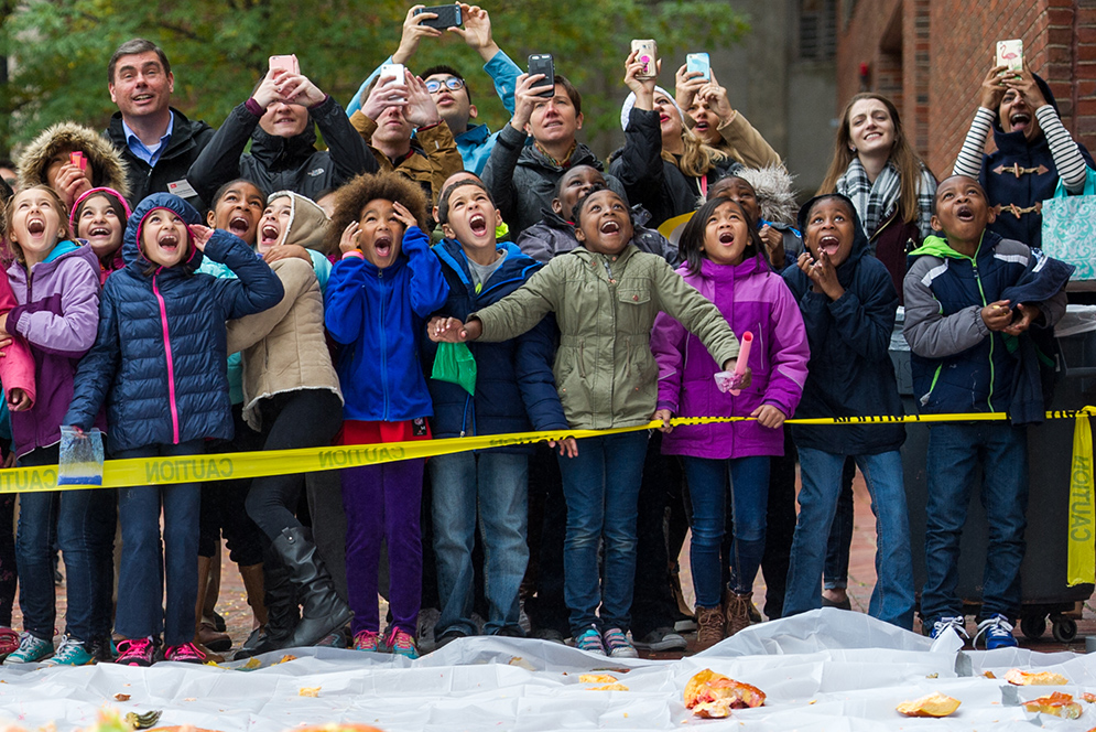 Children and spectators watch as pumpkins are dropped from the rooftop