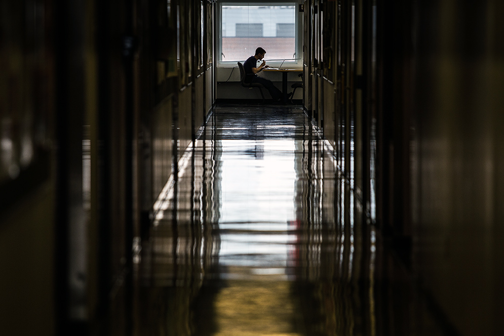 a shot of a long hallway with a student studying 