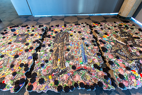 colorful tapestry made of cotton, glitter, plastic, glass, and black crocheted roses and mixed media.