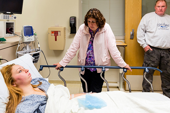 Holly Anderson is in a hospital bed with her mother Claire and father Rick watching over her