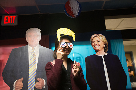 A BU student takes a photo with life size cardboard cutouts of Hillary Clinton and Donald Trump during a third presidential debate watch party at BU Central