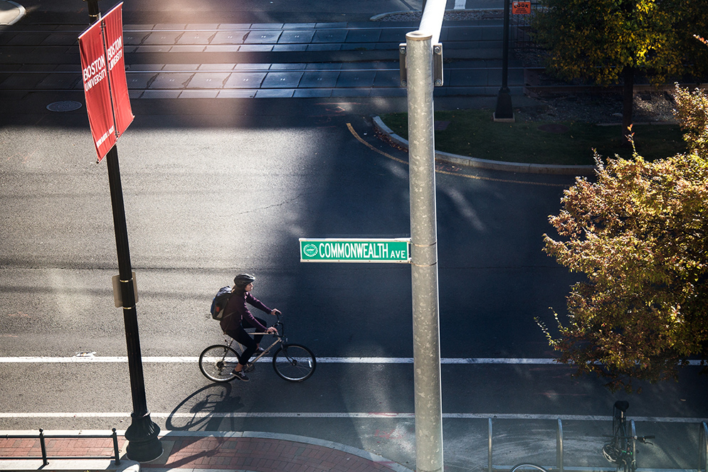 Cyclist bikes past Comm Ave sign