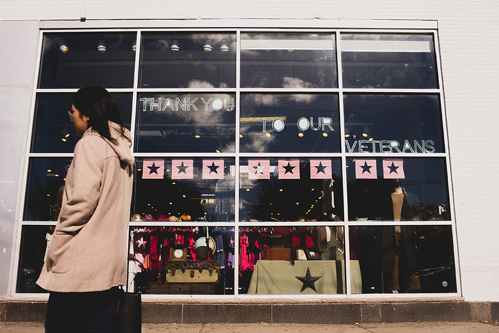 A woman walks by a Goodwill store with a sign that says "Thank you Veterans"