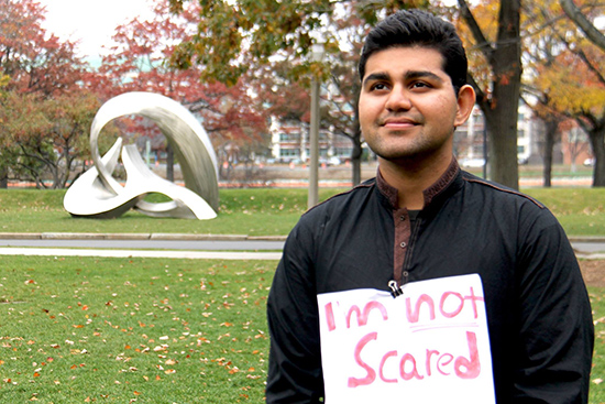 Photo of Ibrahim Rashid wearing a sign the says "I'm not scared"