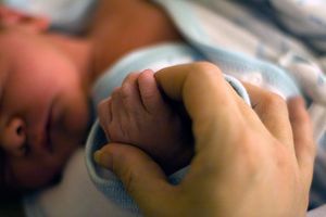 a mother holding a newborn's hand