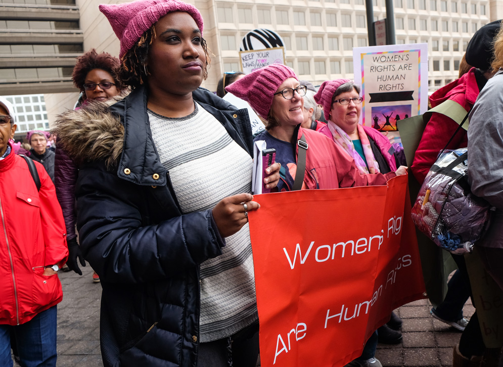 Tiffani Lewis-Lockhart, Ann Cudd, and Nancy Geourntas holding sign