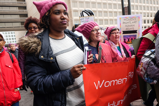 Tiffani Lewis-Lockhart, Ann Cudd, and Nancy Geourntas holding sign