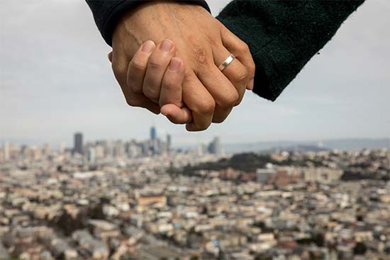 a married couple in san francisco california hold hands with the city in the background