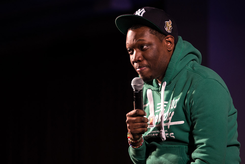 Michael Che holding microphone